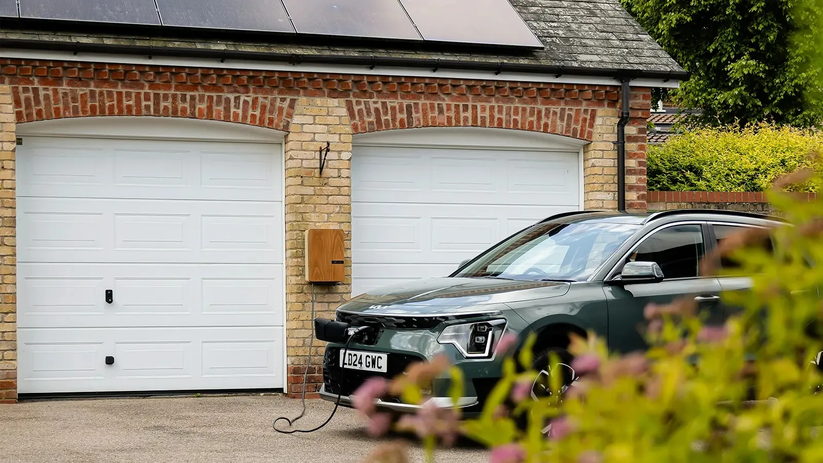 Elbil tilsluttet en ladeboks ved en garage
