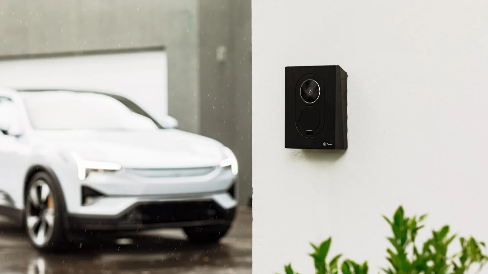 Zaptec Go på en væg ved en parkeret elbil